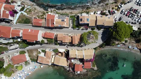Top-down-view-of-houses-on-Greece-peninsula-on-a-sunny-day,-aerial-rising