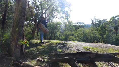 Australian-bushman-with-his-swag-walks-on-to-a-big-rock-outcrop-in-the-Australian-bush