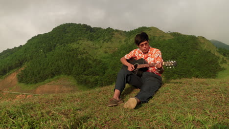 Asian-guitar-player-at-mountain-in-Vietnam,-wide-angle-slow-motion
