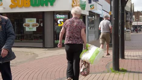 Slow-motion-pensioners-walking-past-subway-in-windy-UK-town-with-closed-shops-in-cost-of-living-crisis