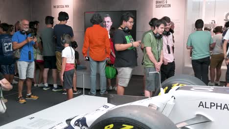 Visitors-look-and-take-photos-of-the-F1-car-racing-Lotus-49,-Alpha-Tauri,-during-the-world's-first-official-Formula-1-exhibition-at-IFEMA-Madrid,-Spain