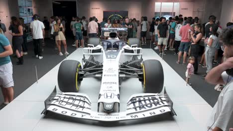 Visitors-and-F1-enthusiasts-look-and-take-photos-of-the-F1-car-racing-Lotus-49,-Alpha-Tauri,-during-the-world's-first-official-Formula-1-exhibition-at-IFEMA-Madrid