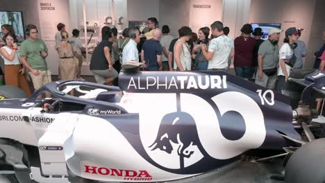 F1-enthusiasts-and-Visitors-look-and-take-photos-of-the-F1-car-racing-Lotus-49,-AlphaTauri,-during-the-world's-first-official-Formula-1-exhibition-at-IFEMA-Madrid