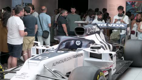Visitors-and-F1-fans-look-and-take-photos-of-the-F1-car-racing-Lotus-49,-Alpha-Tauri,-during-the-world's-first-official-Formula-1-exhibition-at-IFEMA-Madrid