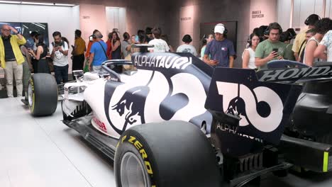 Visitors-and-F1-enthusiasts-look-and-take-photos-of-the-F1-car-racing-Lotus-49,-AlphaTauri,-during-the-world's-first-official-Formula-1-exhibition-at-IFEMA-Madrid