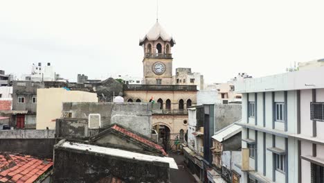 Aerial-drone-camera-moving-towards-the-foreground,-the-very-old-clock-tower-of-Rajkot-known-as-Raya-Naka-Tower