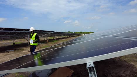 Black-male-African-engineer-walking-in-solar-panel-renewable-energy-farm-with-protective-helmet-carrying-a-paper-notebook-with-measurements-data-of-photovoltaic-plant-efficiency-in-Africa