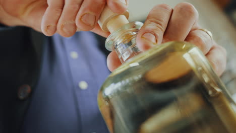 Close-up-shot-of-a-male-expert-putting-a-cap-on-a-glass-bottle-of-distilled-gin,-quality-control-process-in-a-gin-distillery-production