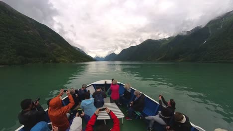 Many-tourists-sailing-glacial-green-Fjaerlandsfjord-and-taking-photos-from-the-bow-of-sightsseing-boat---Wide-angle-handheld-of-boat-in-motion