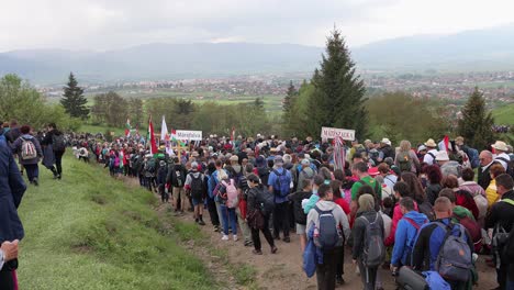 People-walking-down-hill-after-Csiksomlyo-Pilgrimage,-Miercurea-Ciuc-Harghita-mountain-in-background