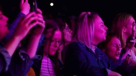 Close-up-of-people-singing-at-concert-at-night-with-lighting