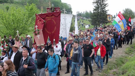 People-carrying-church-flags-from-Gyergyóalfalu-leave-Mass,-Csiksomlyo-Pilgrimage