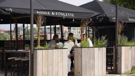 Happy-people-dating-and-talking-at-the-terrace-of-chicken-restaurant-Poule-and-Poulette-in-the-city-of-Antwerp,-Belgium