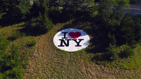 An-aerial-view-of-an-I-Love-New-York-logo-on-the-grass-between-highways-on-Long-Island,-NY-on-a-sunny-day