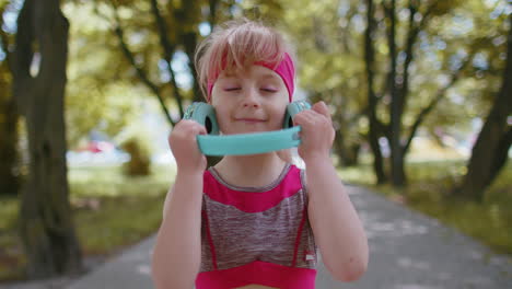 Portrait-of-athletic-sport-runner-child-girl-training,-listening-favorite-music-song-in-headphones