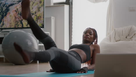 African-slim-woman-morning-workout-in-living-room-doing-scissors-exercise-on-yoga-map