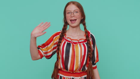 Redheaded-girl-smiling-friendly-at-camera-and-waving-hands-gesturing-hello-or-goodbye,-welcoming