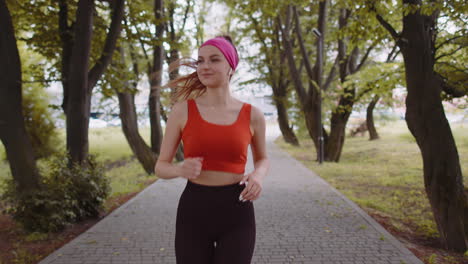 Athletic-fitness-sport-runner-girl-training-marathon-run,-listening-music-in-earphones-oudoors-park
