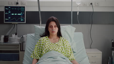 Portrait-of-sick-woman-wearing-nasal-oxygen-tube-resting-in-bed