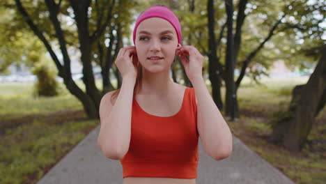 Portrait-of-athletic-sport-runner-girl-training,-listening-favorite-music-song-in-earphones-in-park