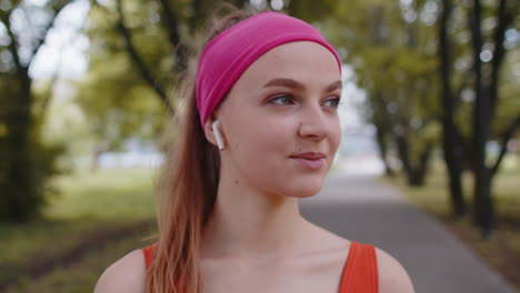 Portrait-of-athletic-sport-runner-girl-training,-listening-favorite-music-song-in-earphones-in-park