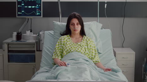 Sick-woman-with-nasal-oxygen-tube-looking-into-camera-resting-in-bed