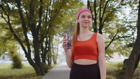Athletic-fit-sport-runner-young-girl-drinking-water-from-bottle-after-training-exercising-in-park