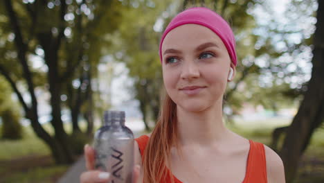 Athletic-fit-sport-jogger-young-woman-drinking-water-from-bottle-after-training-exercising-in-park