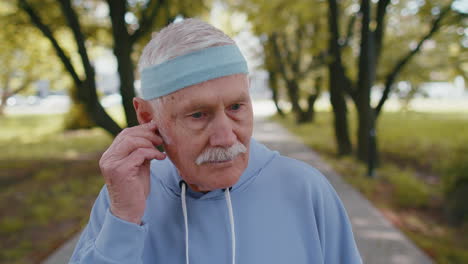 Portrait-of-athletic-senior-sport-runner-man-wearing-earphones-listening-music,-smiling,-cardio