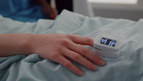 Close-up-of-hospitalized-woman-with-finger-heart-rate-monitor-showing-pulse