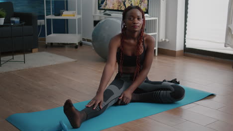 Flexible-fit-black-woman-doing-stretching-routine-on-yoga-map