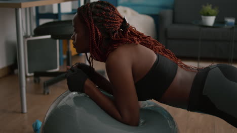 Mujer-Negra-Delgada-Y-Atlética-Estirando-El-Músculo-Abdominal-Mientras-Está-Sentada-En-Una-Pelota-Suiza-De-Yoga-Fitness