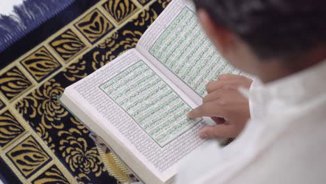 Over-the-shoulder-shot-of-Indian-man-reading-Quran-holy-book