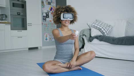 Cheerful-sportswoman-in-VR-glasses-at-home