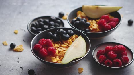 Golden-cornflakes-with-fresh-fruits-of-raspberries,-blueberries-and-pear-in-ceramic-bowl