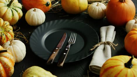 Black-plate-and-cutlery-surrounded-by-pumpkins
