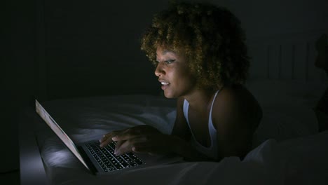 Smiling-woman-chatting-with-laptop-in-dark