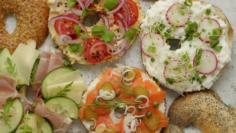 Bagel-sandwiches-with-various-toppings,-salmon,-cottage-cheese,-hummus,-ham,-radish-and-fresh-herbs