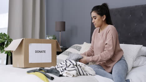 a-woman-packing-clothes-in-a-donation-box-at-home