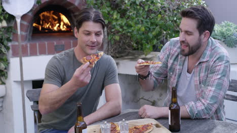 Dos-Hombres-Comiendo-Pizza-Y-Cervezas-Sentados
