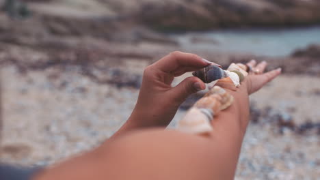 Hands-of-woman-with-shells-on-arm-at-beach