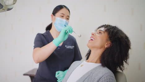 Zahnarzt-Mit-Gesichtsmaske-überprüft-Die-Zähne-Einer-Frau
