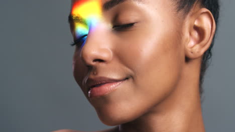 Model-smile-with-rainbow-light-on-face-against