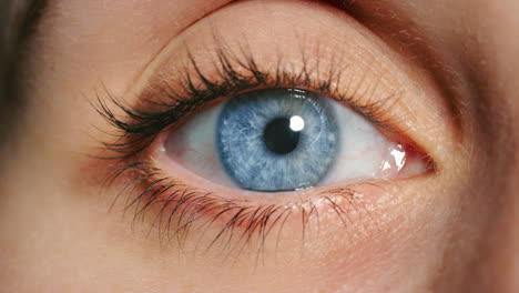 Woman-open-blue-eye,-in-close-up-showing-veins