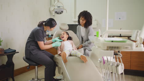 Dentist-examining-little-girls-mouth-during-dental