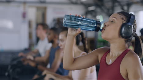 Sweaty-female-athlete-drinking-water-inside-a-busy