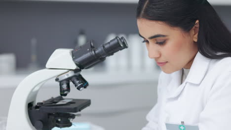 Científico-Femenino-Usando-Un-Microscopio-En-Una-Investigación