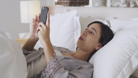 A-young-woman-using-her-phone-while-lying
