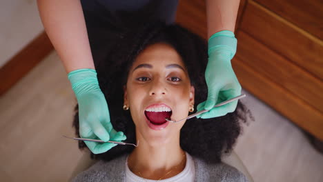 Dentist-checking-mouth-of-female-patient-during