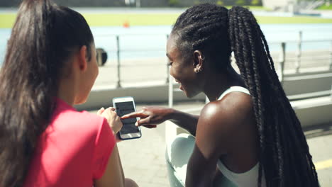 Female-athletes-laughing-while-using-phone